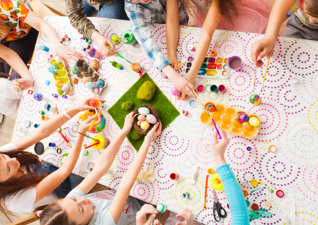Children sat around a table painting eggs.