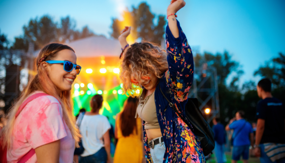 Two girls dancing at a outdoor festival.