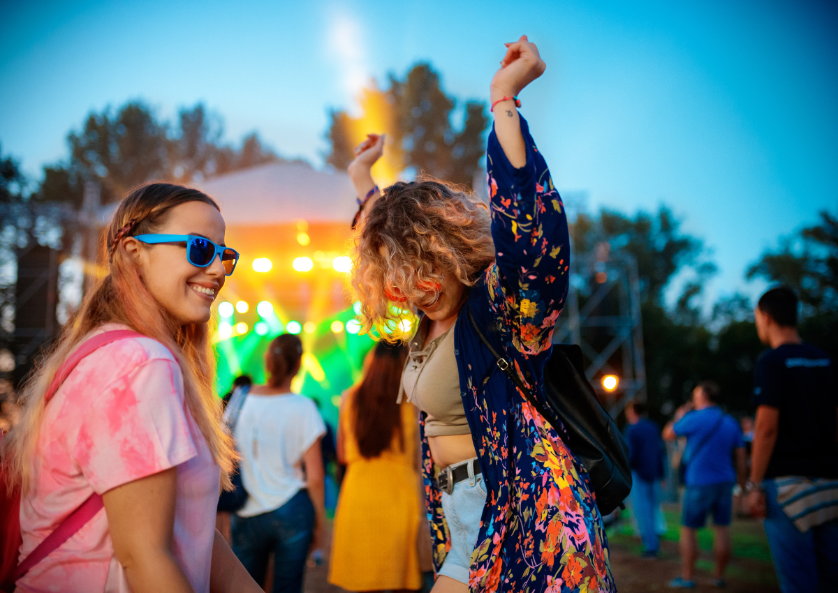 Two girls dancing at a outdoor festival.