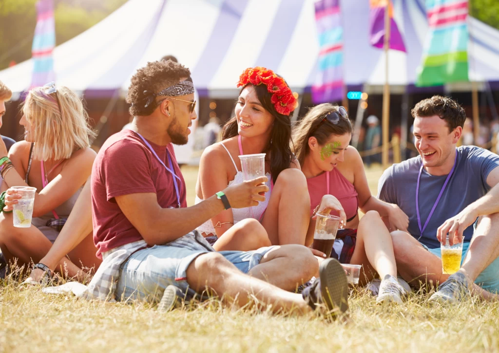 Young adults hanging out and drinking alcohol sitting on the outside area of the festival. 