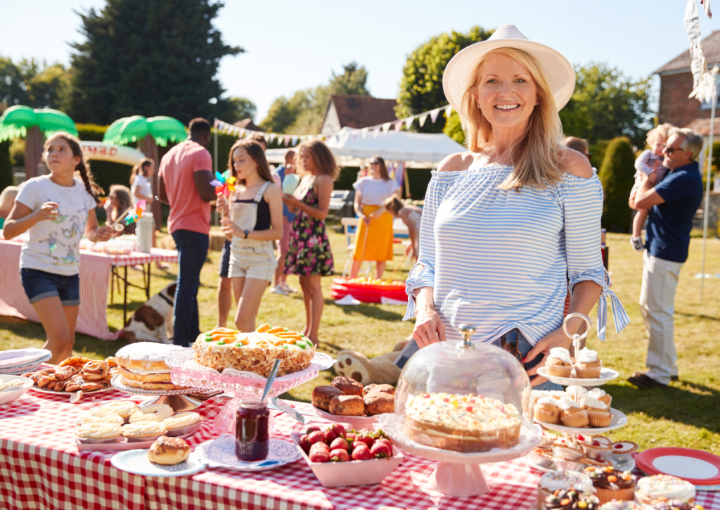 Woman at summer fete serving cakes to families.