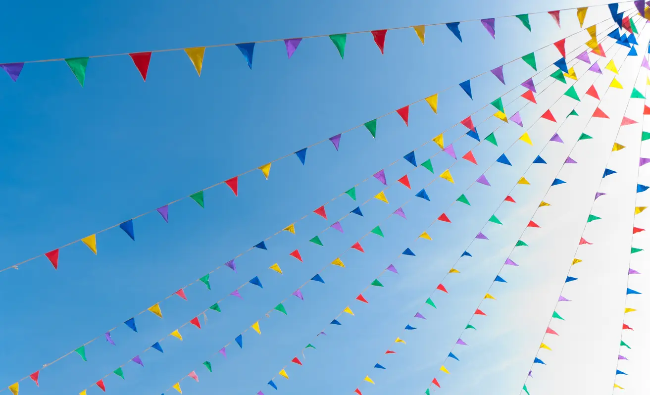 Colourful festival bunting against a blue sky.
